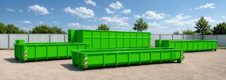 Mehrere grüne Abrollcontainer in unterschiedlichen Größen auf einem Betriebshof, sauber angeordnet für die Containervermietung. @ 
