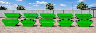 Mehrere grüne Absetzcontainer in verschiedenen Größen auf einem Betriebshof, sauber angeordnet als Übersicht der Containervermietung. @ 